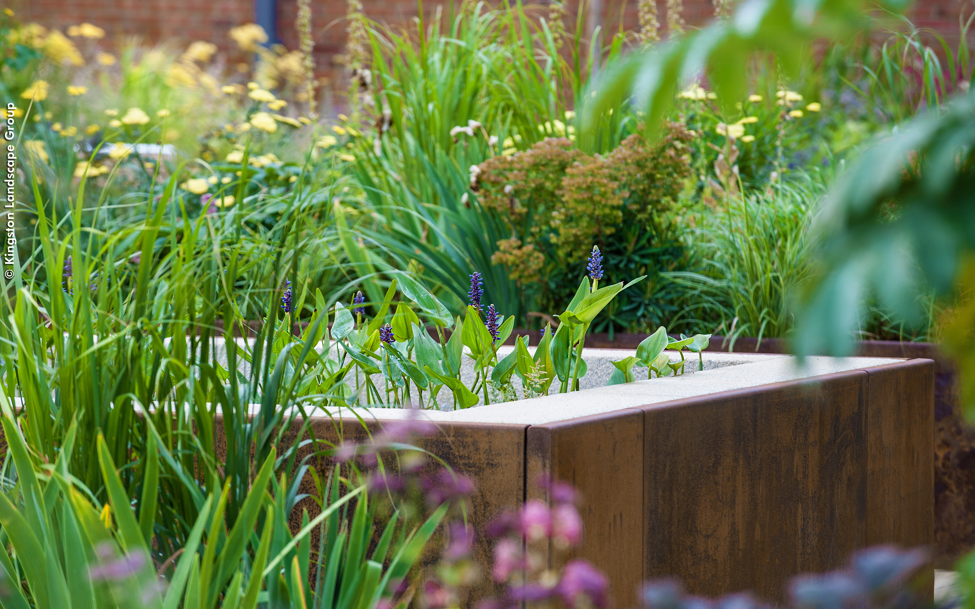 Planter covered with weathered metal and surrounded by greenery